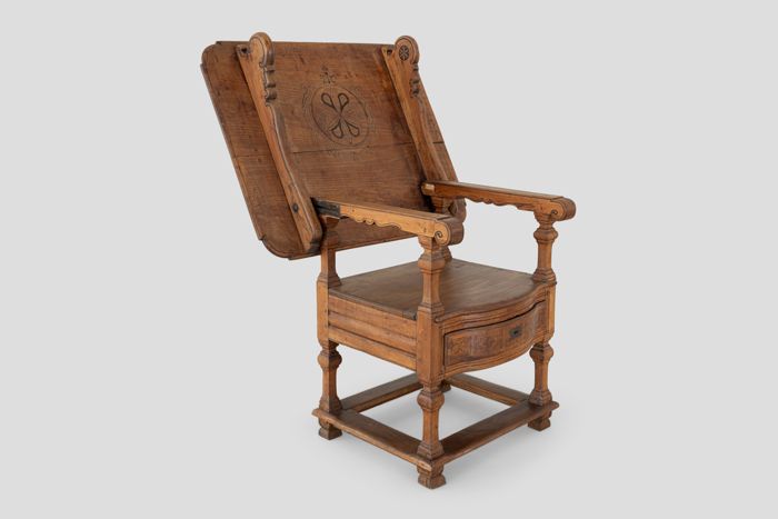 Objektabbildung zoomen Der Stuhltisch mit zurückgeklappter Platte, sodass er als Armlehnstuhl nutzbar ist